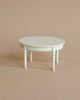 A small, round white table from the Maileg Christmas Room Set with four slender legs.