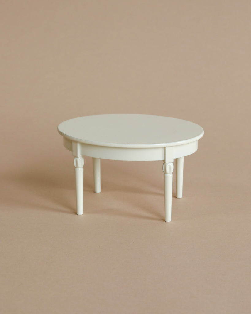 The Maileg Vintage Dining Table, Mouse - Off White is a small, round dollhouse table with four legs, shown on a plain beige background.