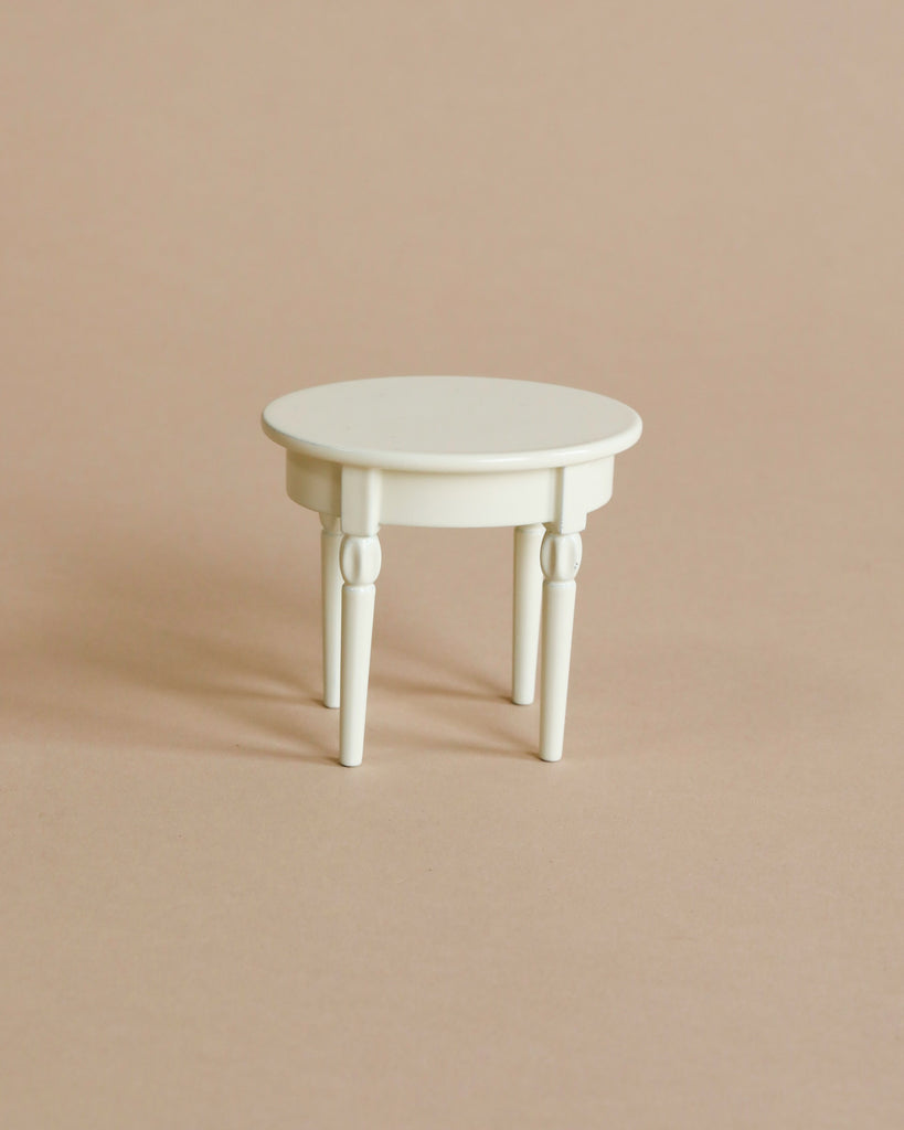 A small, off-white round side table from the Maileg Bathtub Set with four slender, tapered legs.