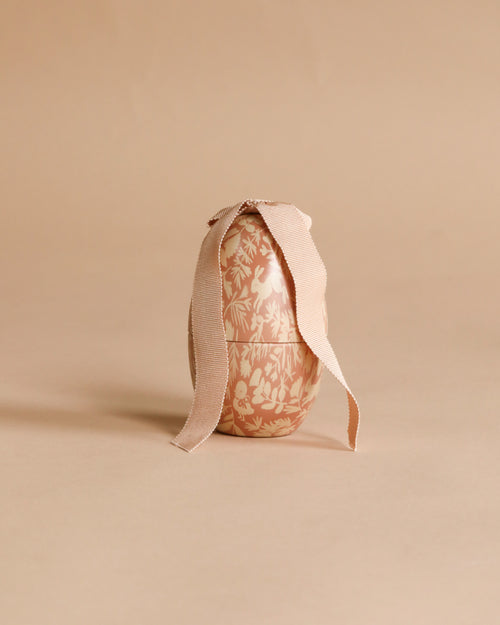 The Maileg Easter Egg, Small - Powder features a floral pattern and a beige ribbon bow, set against a matching background—an ideal decorative accent for Easter celebrations.