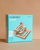 A turquoise box of the Cuboro Wave Marble Run Extra Set, displaying wooden marble run pieces with four marbles arranged on the front. The box stands on a neutral background, highlighting this creative marble run system.