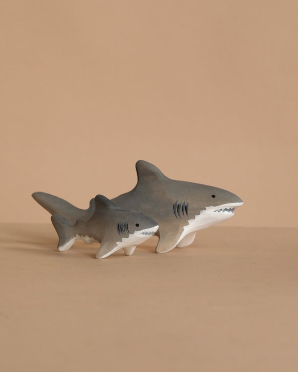 The Bumbu Handmade Wooden Shark Family Set features two gray sharks—one large, one small—with white undersides and black details, displayed on a beige surface, perfect for Montessori play or as a charming decor piece.