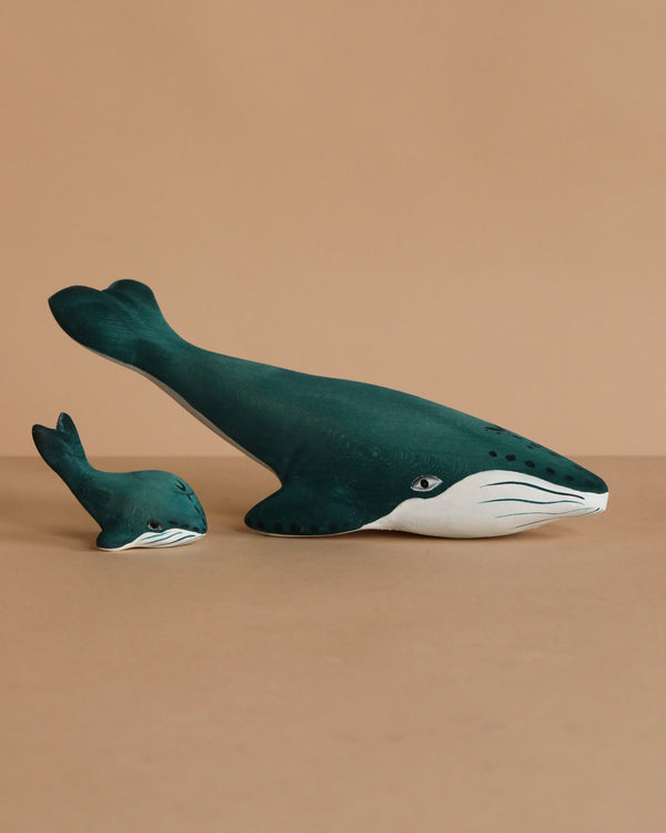 The Bumbu Handmade Wooden Blue Whale Family Set features two sustainably crafted, dark teal wooden whales—one large and one small—with white underbellies, placed side by side for inviting Montessori play.