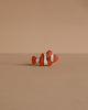 A small orange and white clownfish from the Handmade Holzwald Underwater World Set rests on a plain beige surface with a matching beige background.