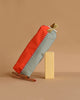 The Sticky Lemon Pencil Case | Color Blocking | Lifebuoy Orange + Shark Grey, made from recycled PET bottles, stands upright next to two colored pencils on a beige background, highlighting its orange and gray color block design.