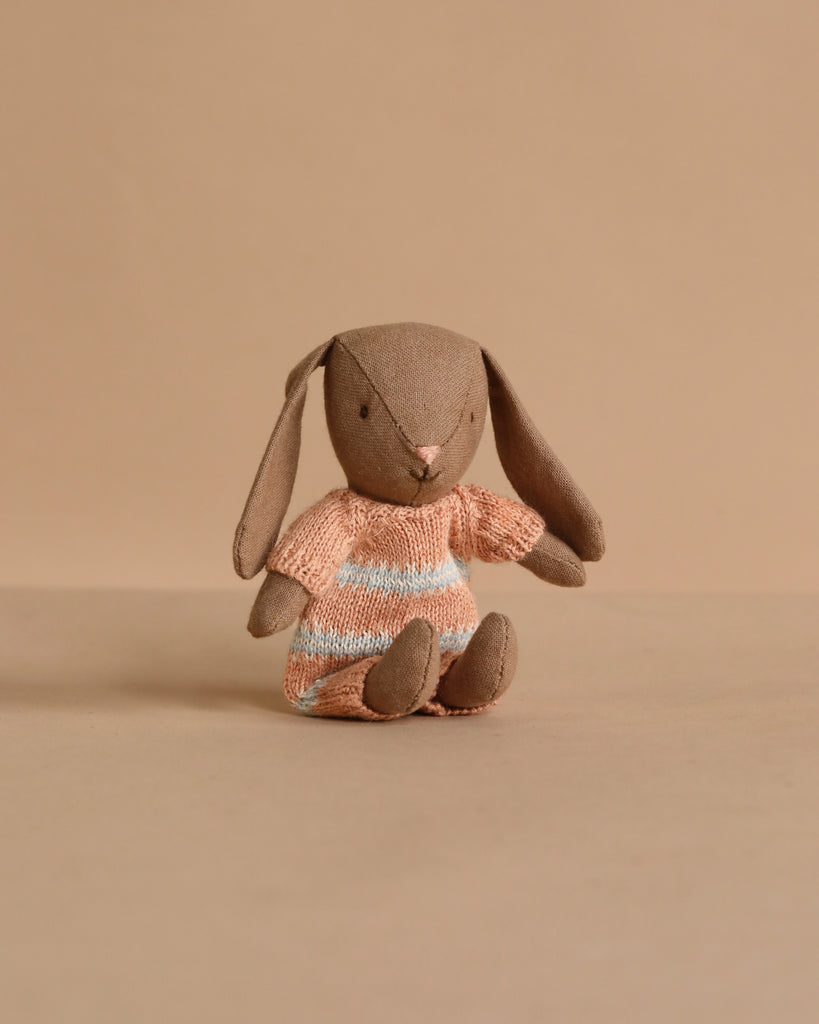 The Maileg Bunny, Micro - Brown wears a dusty rose knitted suit and sits upright, making it a charming addition to your miniature dollhouse or perfect for pairing with Maileg accessories.