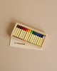A box of Stockmar Wax Stick Crayons Wooden Box - 16 Assorted with various colors displayed in an open white cardboard box on a light beige background.