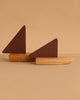 The Ferm Living Opty Boat - Set of 2 features abstract decorative boats with FSC certified oak bases and dark brown triangular sails, shown against a beige background for a timeless design accent.