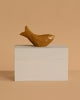 The Ferm Living Hand Carved Wooden Harbour Box - Fish features a small, brown wooden fish with a simple design on a hand-carved box, making it a charming decor piece for children's rooms against a beige background.
