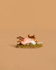 The Wee Forest Folk Tiny Collectible - Meadow Musing (Not a Toy) features a hand-sculpted brown squirrel lying beside a pink object on a textured green base with blue flowers, set against a plain beige background.