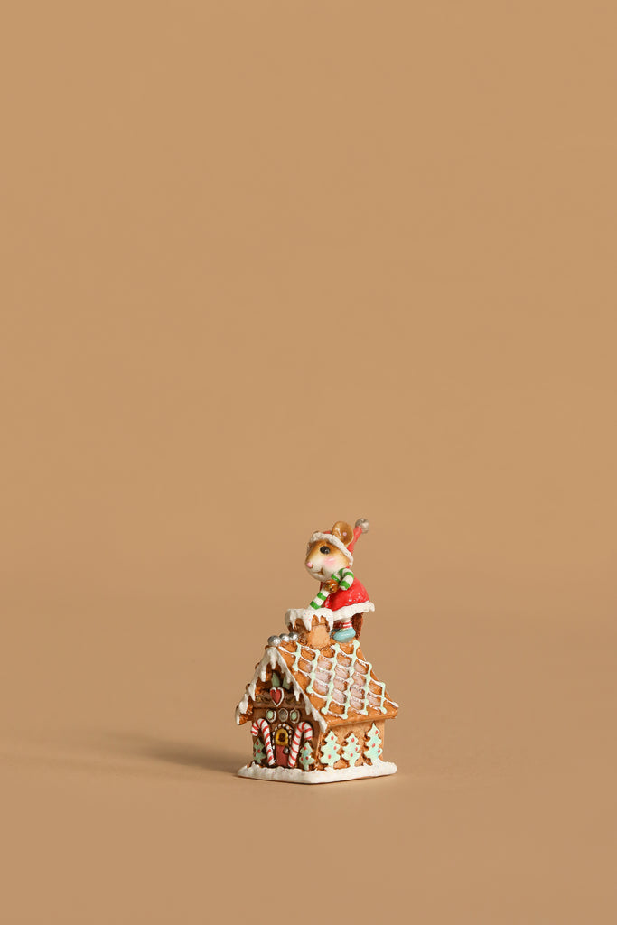 The Wee Forest Folk Tiny Collectible - Santa's Gingerbread House features a small reindeer in a red scarf on the festive roof, handcrafted by New England artisans, and shown against a plain light brown background with ample empty space.