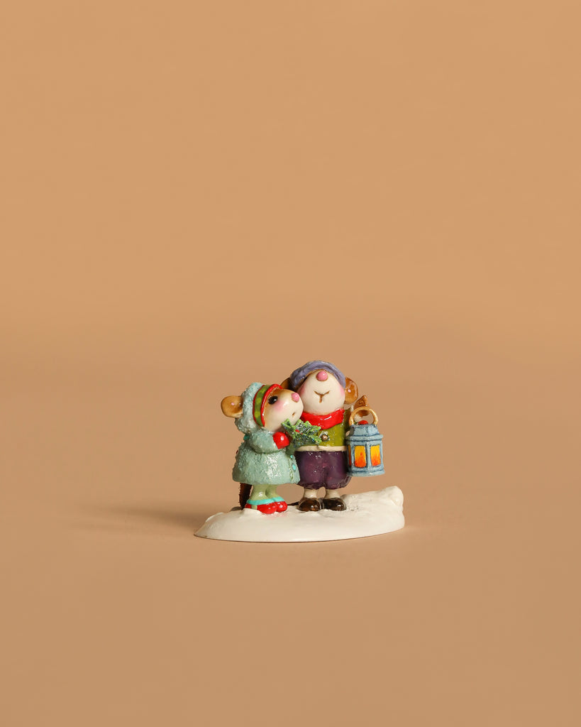 The Wee Forest Folk Tiny Collectible - The Little Wanderers features two mice in winter clothes on a snowy patch—one holding a lantern, the other snuggling close—set against a plain beige background.