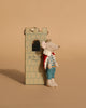 A Maileg Fairytale Set is displayed with a mouse dressed as a king leaning against a charming castle tower, which features a window and the phrase “Let the Story begin.” Beige background.