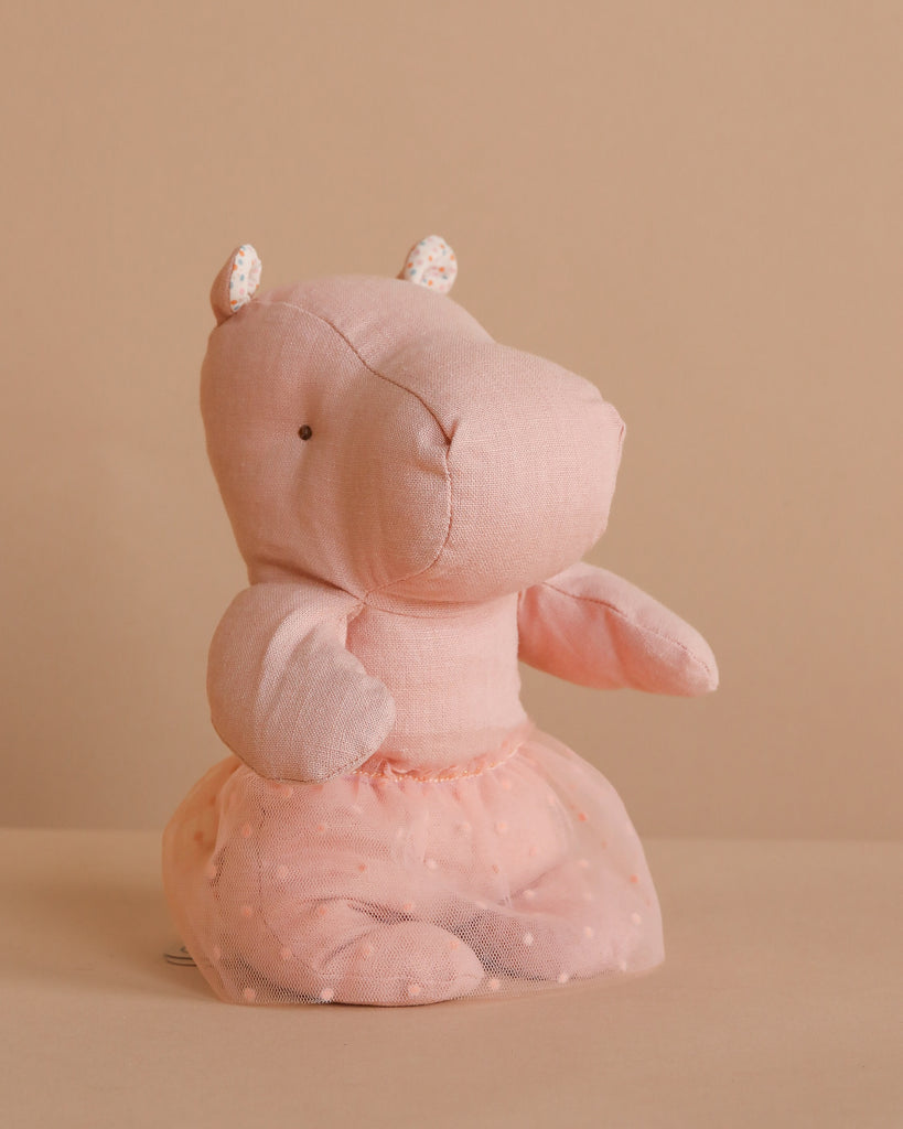 The Maileg Small Hippo With Skirt Stuffed Animal - Soft Rose sits upright against a beige background, dressed in a sheer polka-dot ballerina skirt with small floral-print ears and a charming, minimalist design.