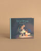 The Maileg LouiMax - Dreams Of Being An Adult Book is a charming children’s storybook featuring LouiMax the mouse holding a mug near a lantern and kettle, with a tent on the beige cover background.