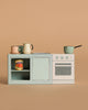 The Maileg Suitcasa Furnished Set—a small toy kitchen featuring pastel dishes, a can of tomatoes, a pot, and a stove—is perfectly sized as Maileg mouse furniture or charming Maileg dollhouse accessories, set against a plain beige background.