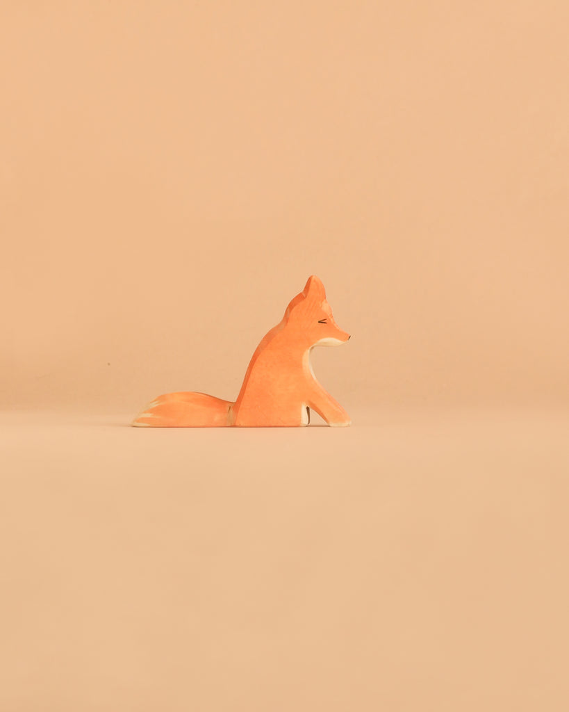 An Ostheimer Handmade Wooden Woodland Animals Set fox figurine, crafted in a minimalist style and inspired by traditional handcrafted toys, sits on a plain beige background, facing to the right.