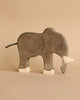 A Holztiger Handmade Wooden Safari Animals Set elephant, hand-painted in gray and white, stands on a beige surface. Its simple handcrafted details inspire imaginative play in any environment.