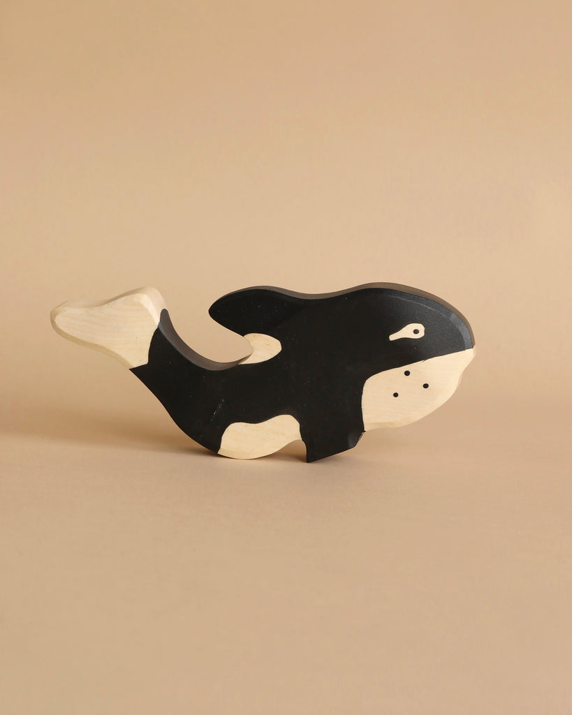 Part of the Holztiger Handmade Wooden Ocean Animals Set, this black and white wooden orca figure stands out against a plain beige background—a charming addition to any wooden animal collection.