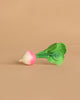 Ramona the Radish Teething Toy, featuring green leaves and a white-and-pink root, rests on a plain beige background—an ideal natural rubber baby toy for sensory play.