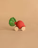 Betty The Beetroot Baby Car, an eco-friendly toy with a red beetroot shape, green leaves, and four wooden wheels, is shown on a plain beige background.