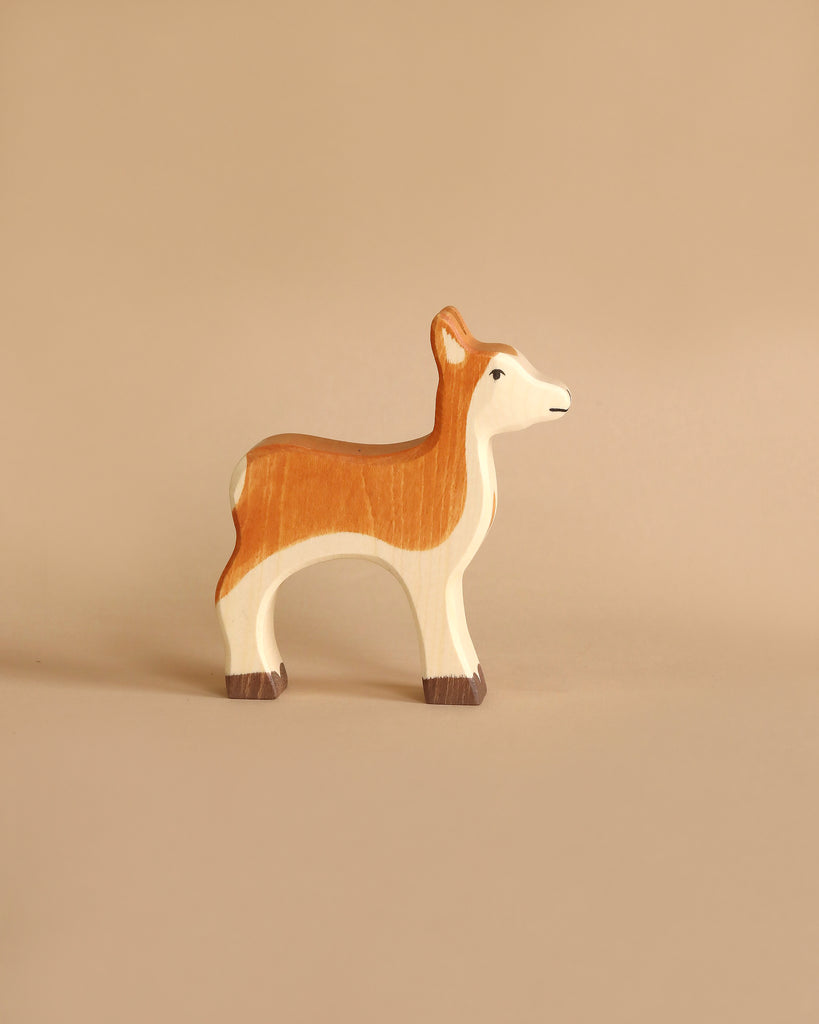 Handcrafted wooden fawn figurine from the Holztiger Handmade Wooden Woodland Animals Set, depicted in profile and painted in shades of brown and cream, perfect for imaginative play.