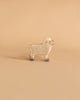 A wooden toy sheep with a light tan body, grey hooves, and subtle circular patterns is standing on a beige background. Handcrafted in Europe, this Holztiger Lamb boasts a simple and minimalist design.