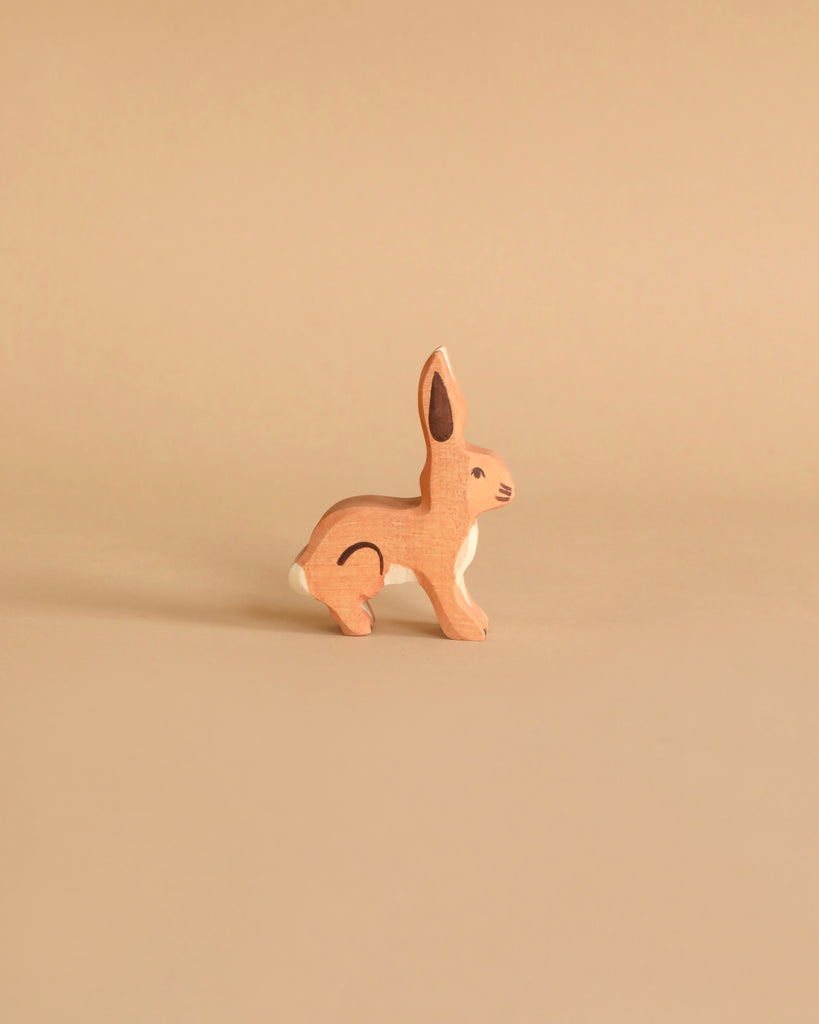 A Holztiger Handmade Wooden Farm Animals Set figurine of a brown rabbit standing in profile.