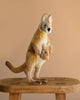 The Kangaroo Mom Stuffed Animal, featuring a baby joey in its pouch and crafted in the style of HANSA animals, stands on a wooden stool against a plain beige background.