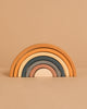 The Handmade Rainbow Stacker - Mustard features five wooden arches in muted earth tones, crafted with non-toxic paint for safe play. Arches stack from largest to smallest and are pictured on a beige background.