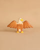 A small, individually handcrafted wooden figurine of a bird with outstretched wings. Made from durable maple and beech wood, the Holztiger Eagle has a white head, a yellow beak, and brown body and wings, presented against a beige background. A charming addition to any HOLZTIGER figures collection.