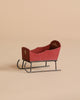 The Maileg Sleigh, Mouse - Red is a small, vintage-style wooden sleigh with metal runners, hand-painted details, and a simple decorative motif on the backrest, shown on a neutral beige background.