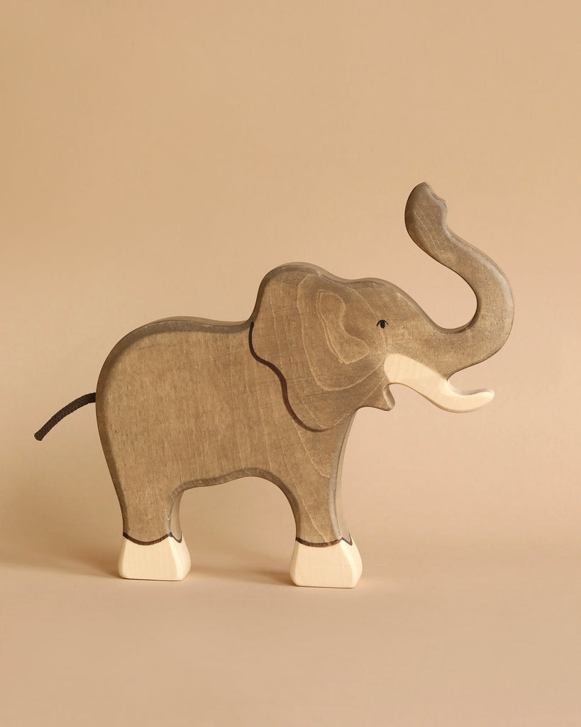 A Holztiger Handmade Wooden Elephant Family Set handcrafted wooden elephant with its trunk raised and cream-colored feet, perfect for open-ended play.