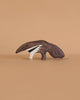 The Holztiger Anteater, a handcrafted wooden toy, features a painted anteater design and sits on a light brown surface with a beige background, showcasing the quality of Holztiger figures made in Europe.