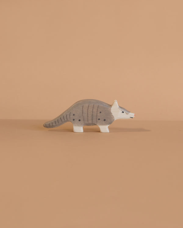 The Holztiger Armadillo is a small, gray wooden figurine with black spots and a white face, handcrafted in Europe, capturing the charm and quality of classic HOLZTIGER toys.