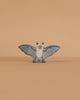 The Holztiger Bat is a small, blue and white wooden figurine with outstretched wings, standing on a smooth light beige surface against a matching background. This handcrafted toy captures the classic style of HOLZTIGER figures.