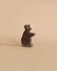 A small, dark handcrafted Holztiger Handmade Wooden Woodland Animals Set toy bear standing on its hind legs.