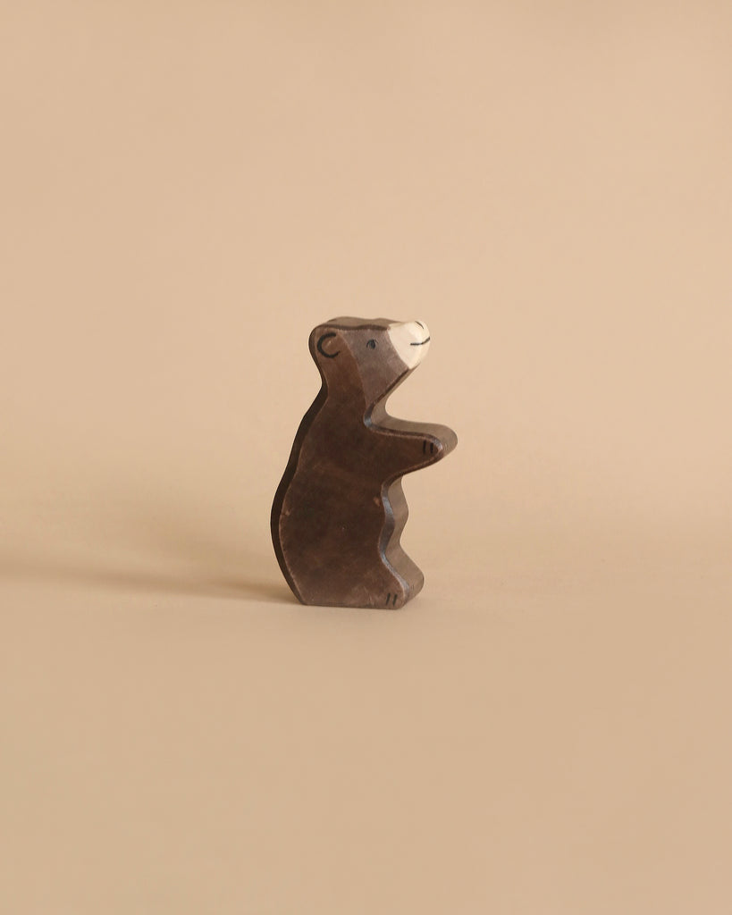 A small, dark handcrafted Holztiger Handmade Wooden Woodland Animals Set toy bear standing on its hind legs.