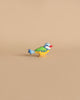 A small wooden bird figure painted in bright pastel colors stands against a plain beige background. The bird has a blue head and tail, green wings, yellow body, and a red beak. This delightful piece is reminiscent of the Holztiger Eurasian Blue Bird, reflecting the charm of handcrafted wood toys as it faces left.