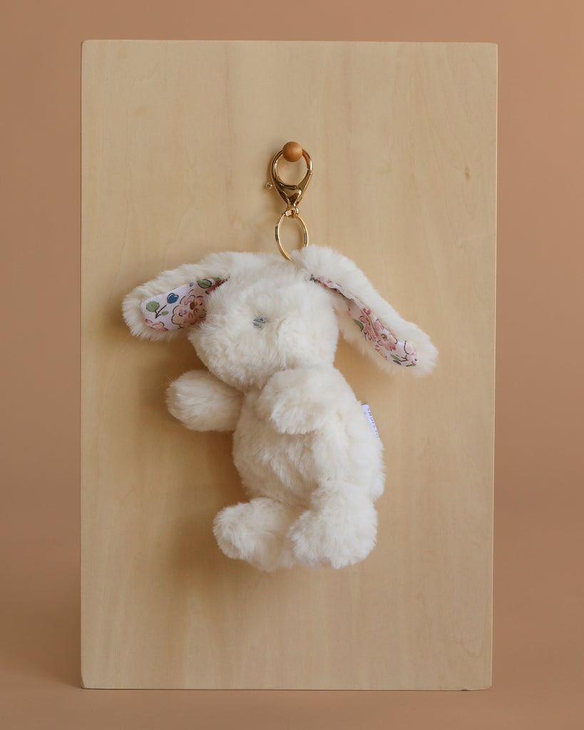 The Mon Ami Bunny Keychain / Bag Charm is a fluffy white bunny with floral-patterned inner ears and a gold clasp, perfect for hanging on your bag or keys. This soft plush accessory adds a cute touch to any collection.