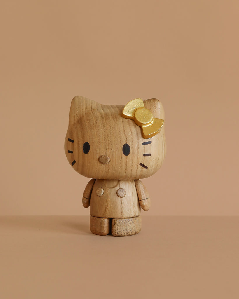 The Boyhood Hello Kitty 50th Anniversary Limited Edition is a wooden collectible with a yellow bow on its left ear, simple black features, and a smooth, rounded finish—perfect for fans of unique Hello Kitty figurines.