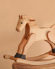 The Spring Copenhagen Wooden Rocking Horse – Final Sale features a natural finish and minimalist Nordic design, displayed on a wooden surface with a beige background for an elegant look.