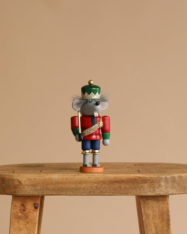 A Christian Ulbricht Collectible Wooden Nutcracker - Mouse King stands on a wooden stool against a plain beige background.