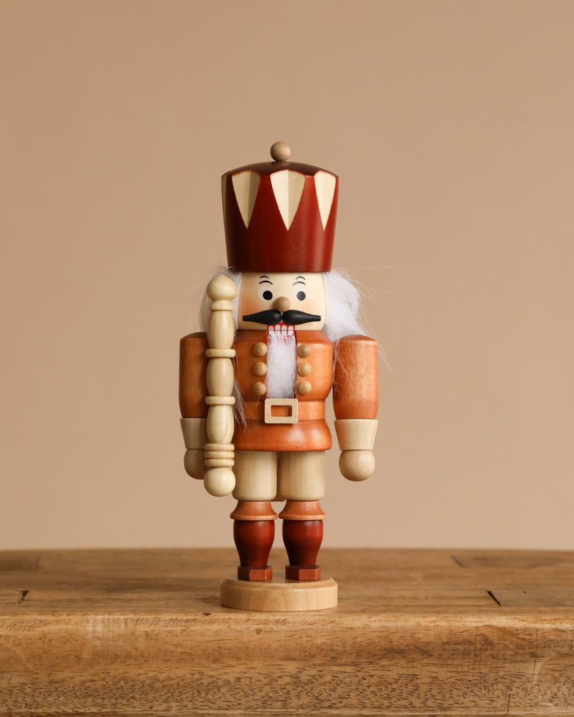 The Christian Ulbricht Collectible Wooden Nutcracker - King (Natural) stands on a rustic wooden surface against a plain beige background.
