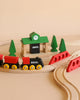 The BRIO World Train Set Classic Figure 8 Set features classic red and black trains on curved tracks, with red bridges, green pine trees, and a green station—crafted in timeless Scandinavian design.