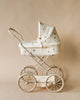 The Konges Sloejd Doll Pram - Lemon features large wheels, a curved handle, quilted fabric with small floral prints, and a hood. It includes an organic cotton mattress for comfort and comes in a neutral beige color.