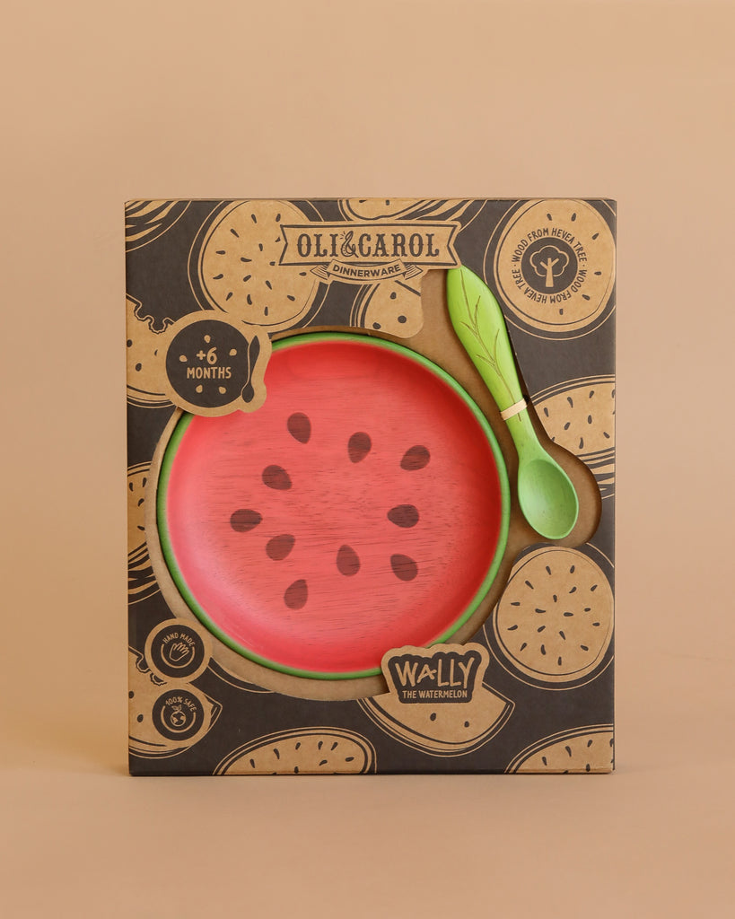 The Wally the Watermelon Plate & Spoon Set includes a watermelon-themed Hevea wood plate and green spoon in non-toxic packaging with fruit designs, labeled "Oli&Carol," and suitable for babies 6 months and older.