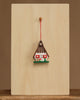 The Christian Ulbricht Ornament - Gingerbread House is a small, decorative wooden ornament with heart details, hanging on a red string from a peg on a light wooden board. Contains small parts; choking hazard. Made in Germany.