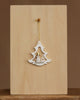 The Christian Ulbricht Ornament - White Tree with Snowman is a 3.5-inch wooden Christmas tree ornament featuring a small snowman and two trees, hanging by a gold string against a plain light wood background.