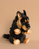 A German Shepherd Dog Puppet is positioned upright against a simple beige background. This handcrafted puppet showcases realistic features, including a fluffy black and tan coat, intricate facial details, and soft paw pads.